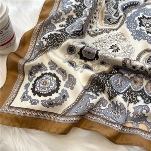 Detail view of retro paisley silk scarf with muted brown and beige tones on fur mat