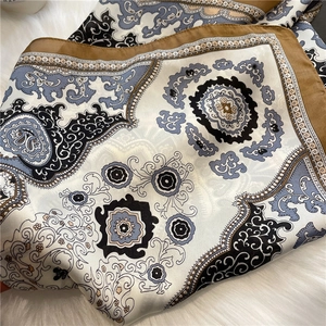 Close-up of paisley pattern on silk-like scarf over white faux fur background