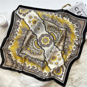 Detailed texture of ginger paisley satin scarf on a soft white plush background