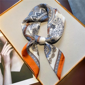 Detail of paisley pattern silk square scarf with orange borders on display board