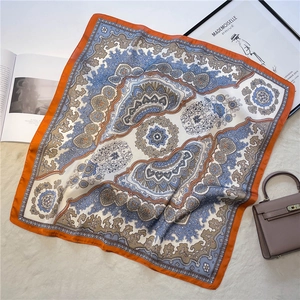 Detail of silk-feel square scarf with paisley pattern on beige faux fur background