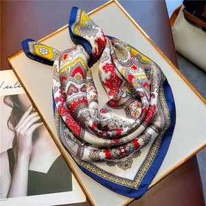 Close-up of silk square scarf with baroque patterns on a beige jewelry display tray