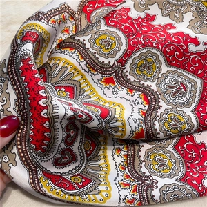 Close-up of silky square scarf with vintage red paisley pattern and glossy texture