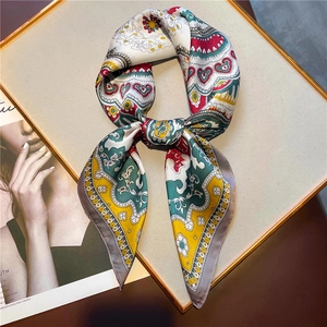 Detail of printed silk square scarf with paisley pattern on gold display board