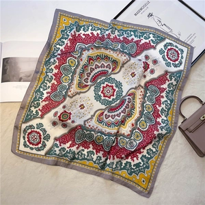 Detail of bohemian silk-like square scarf with paisley print on soft textured background