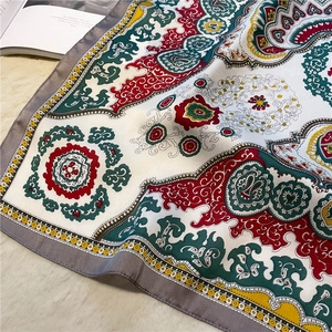 Close-up of silk scarf with paisley floral pattern on a soft cream background