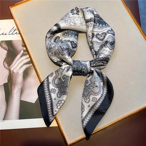 Close-up of black and white paisley silk scarf tied in a bow on a display board