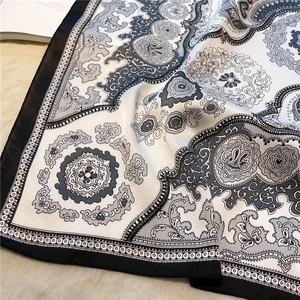 Detailed view of paisley silk-like scarf with soft folds on white faux fur background