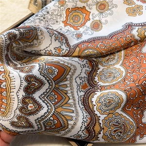 Detailed macro view of satin silk scarf with orange paisley and heart patterns