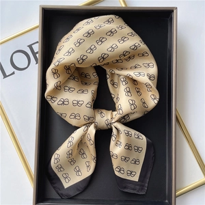 Elegant champagne silk scarf with black bow patterns in a premium gift box setup