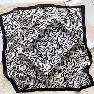 Flat lay detail of black and white zebra print silk scarf on a white plush rug background