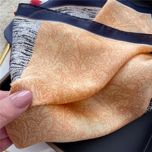Macro shot of orange and navy silk scarf with paisley pattern and smooth satin texture
