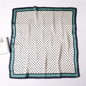 Detail of silk-like square scarf with polka dots and contrasting green navy borders