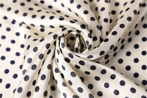 Detailed view of silk-like satin fabric texture with elegant black polka dot pattern