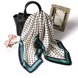 French style polka dot silk scarf draped over a black handbag with fashion accessories