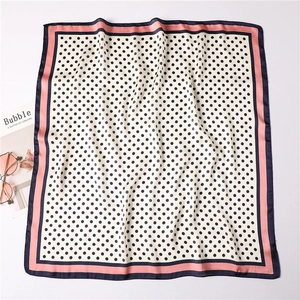 Close-up of silk square scarf featuring polka dots and pink-blue color block edges