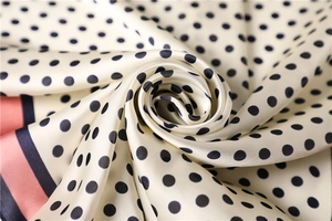 Macro detail of satin silk scarf showing polka dots and premium draped texture