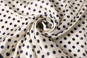 Macro view of creamy white satin scarf with black polka dots and silky texture