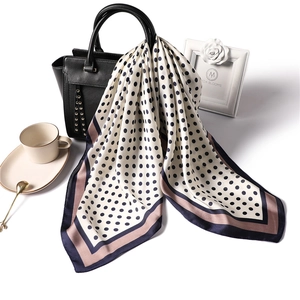 Chic square silk scarf with black polka dots draped on handbag for professional styling