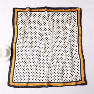 Detailed flat lay of silk-feel square scarf featuring black polka dots and contrast borders