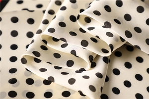 Close-up of silky polka dot neck scarf fabric showing smooth texture and sheen