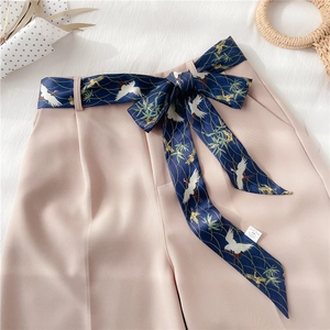 Détail d'un pantalon rose tendre avec une ceinture en soie à imprimé grue élégant