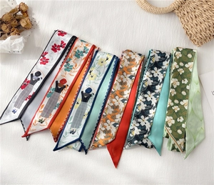 Mise à plat de plusieurs foulards étroits en satin avec motifs floraux et personnages