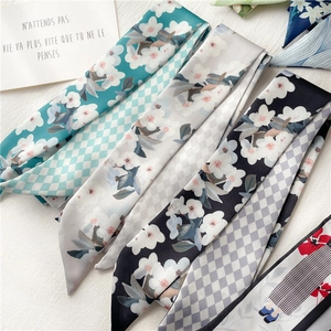 Vue détaillée de plusieurs foulards étroits en soie imprimée sur un tissu blanc