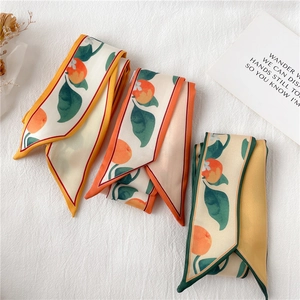 Détail de foulards longs et étroits à motif orange en jaune, rouge et vert