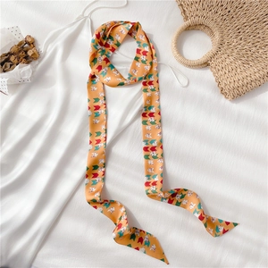 Détail d'un long foulard en soie orange avec motif géométrique et imprimé chat