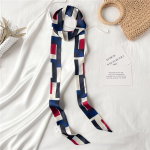 Mise à plat d'un foulard étroit en soie imprimée sur une robe blanche et décor élégant