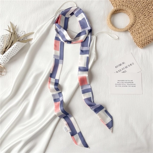 Détail d'un foulard étroit en satin géométrique assorti à une robe en soie blanche élégante