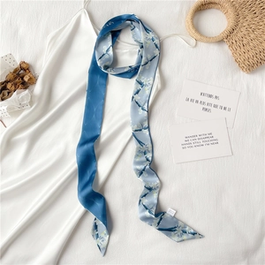 Détail d'un foulard étroit à imprimé floral stylisé sur une robe en soie blanche élégante