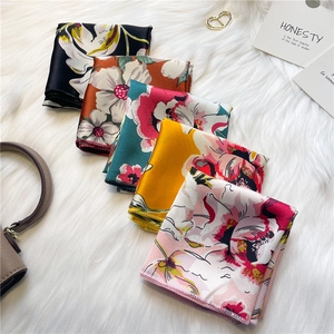 Détail de foulards carrés en satin aux imprimés floraux variés sur un fond en peluche douce