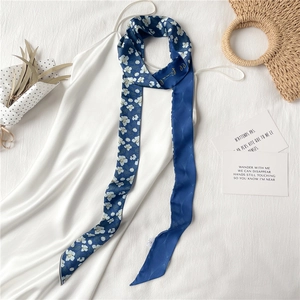 Gros plan d'une écharpe fine à fleurs bleu marine drapée sur une robe blanche