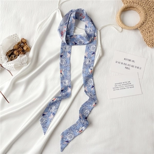Détail d'un foulard en soie bleue avec imprimé fleurs et oiseaux sur une robe satinée