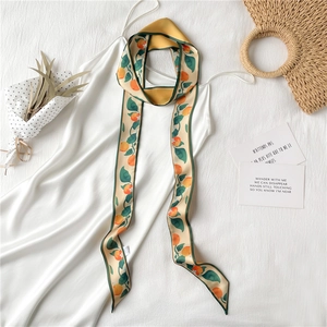 Détail d'un foulard étroit Twilly à imprimé oranges sur une robe en satin perle