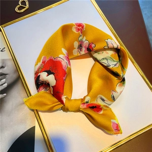 Détail d'un foulard en soie jaune vif noué avec d'élégants motifs de roses rouges