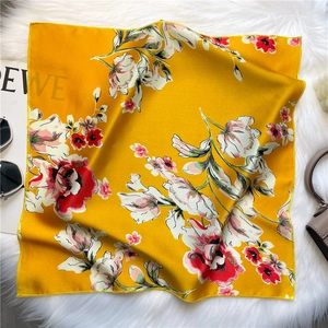 Détail du foulard en soie jaune à motif floral avec ourlet roulé sur fond peluche