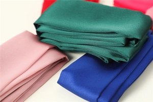 Close-up of multicolored silk-textured scarves in dark green, royal blue, and red tones