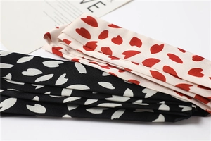 Detailed view of floral print skinny scarves in black and beige silk-like fabric