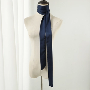Detail view of a long navy blue satin silk scarf tied elegantly around a mannequin neck
