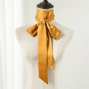 Detail of a golden mustard satin skinny scarf tied in an elegant bow on a mannequin