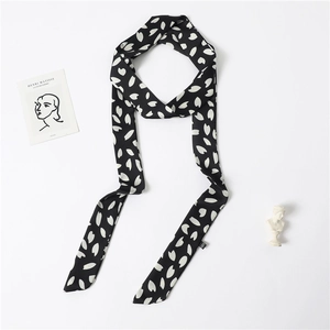 Detail of a long black silk-like scarf with white floral patterns and artistic texture