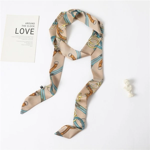 Detail shot of a beige silk twilly scarf with horse harness patterns on a white background