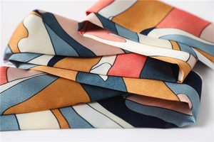 Macro shot of colorful satin silk scarf featuring abstract geometric flow patterns and texture