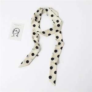 Detailed view of an elegant cream long narrow scarf with classic black polka dots pattern