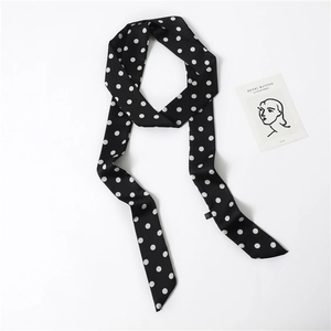 Close-up of black silk-like skinny scarf with white polka dots and artistic card detail