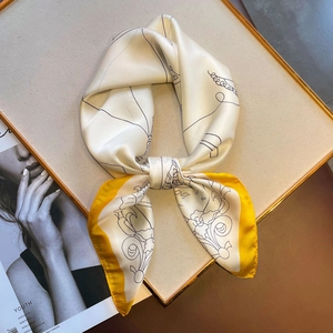 Nahaufnahme eines eleganten Seidenschals in Creme mit gelbem Rand und floralem Muster
