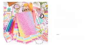 Detail of DIY journal kit featuring pink glitter notebook and varied art accessories